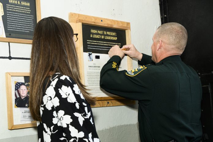 Sheriff Robert A. Hardwick places his retired badge on display at the Old Jail as his wife, Kendell, looks on photo credit Ed Taylor