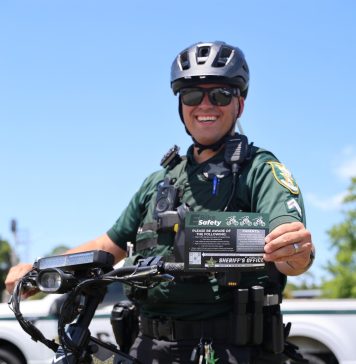 Cpl. Michael Ettel displays the St. Johns County Sheriff’s Office e-bike safety card, which outlines the differences between electric bicycle classes and illegal e-motos. Photo courtesy St. Johns County Sheriff's Office