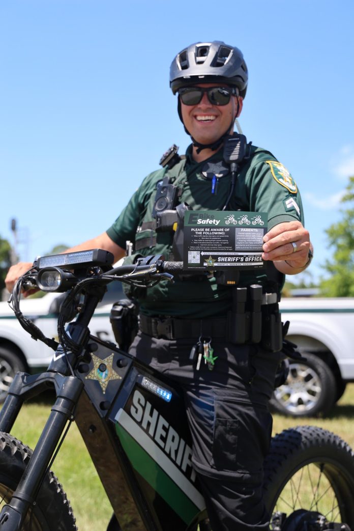 Cpl. Michael Ettel displays the St. Johns County Sheriff’s Office e-bike safety card, which outlines the differences between electric bicycle classes and illegal e-motos. Photo courtesy St. Johns County Sheriff's Office