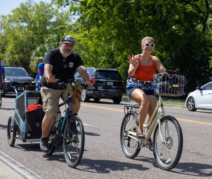 Cyclists wave to onlookers as they ride together during the Duval Day Bike Tour. Photo by Emily Delaney