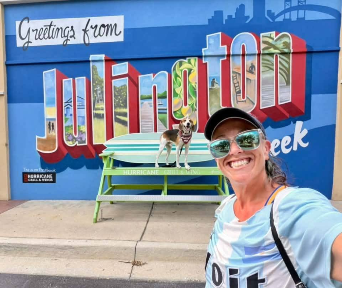 Lyndsay and Cooper Lindsay Brown and her dog, Cooper, pose in front of the new mural outside Hurricane Grill & Wings in Julington Creek. Photo by Lindsay Brown