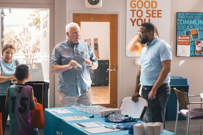 A member speaks with a First Coast YMCA staff member at a health and wellness table. Photo courtesy First Coast YMCA